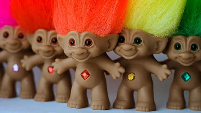 it's a picture of troll dolls. honestly I'd probably be doing you a favor not describing them, but if you must know: wretched works of a heretic's hand. stumpy little things that look like baby yoda going through a divorce. no human has ever been that shade of gray-beige but a lot of depressing house flip walls have. neon hair standing straight up. terrible, terrible eye contact, all iris/pupil, no sclera. a single gem embedded in their abdomen like the hourglass on a black widow; arms widespread and open. never should have been born. 7/10.