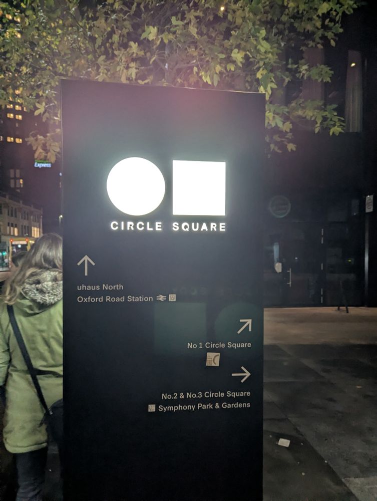 Illuminated street sign pointing towards Circle Square