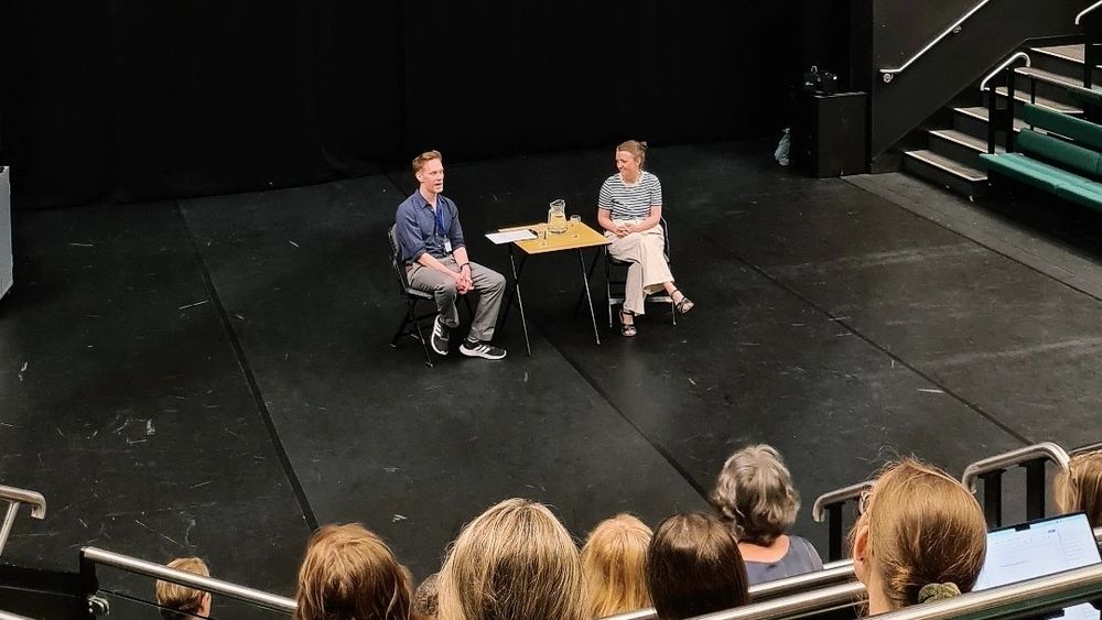 Director Amy Leach sits talking to Mark Love-Smith on a large auditorium stage at the University of York 