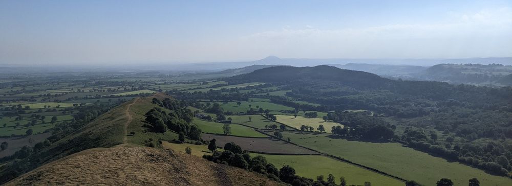 The view north from The Lawley, a "ridge-backed" hill in Shropshire near Church Stretton, looking towards the Shropshire Plain and the horizon-piercing peak of The Wrekin, most famous of the Shropshire Hills.