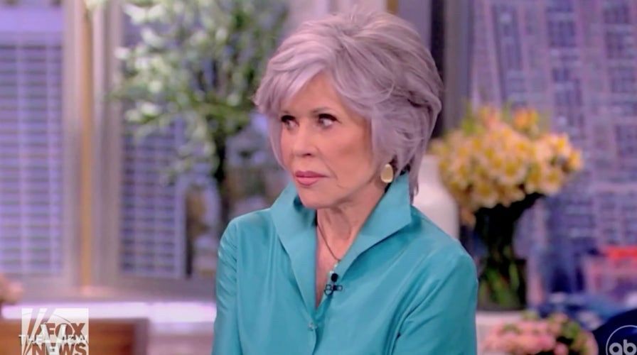 Jane Fonda in turquoise coat with silver hair from her appearance on The View where she suggested murder is the next stage after protests are ignored. She looks disapprovingly at the other hosts as they suggest she was kidding. 