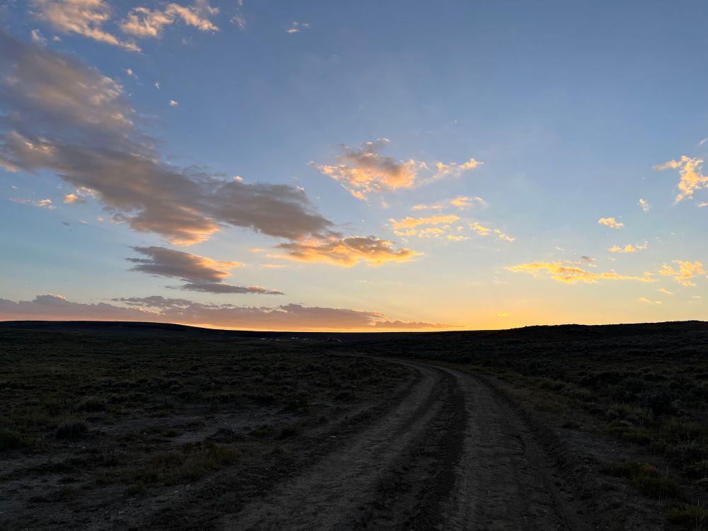 photo of an orange sunset over a dark, open sagebrush landscape