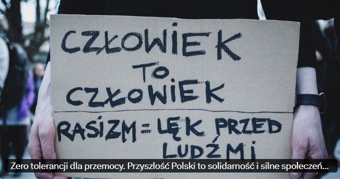 Osoba trzyma tabliczkę z napisem "Człowiek to człowiek. Rasizm = lęk przed ludźmi"
