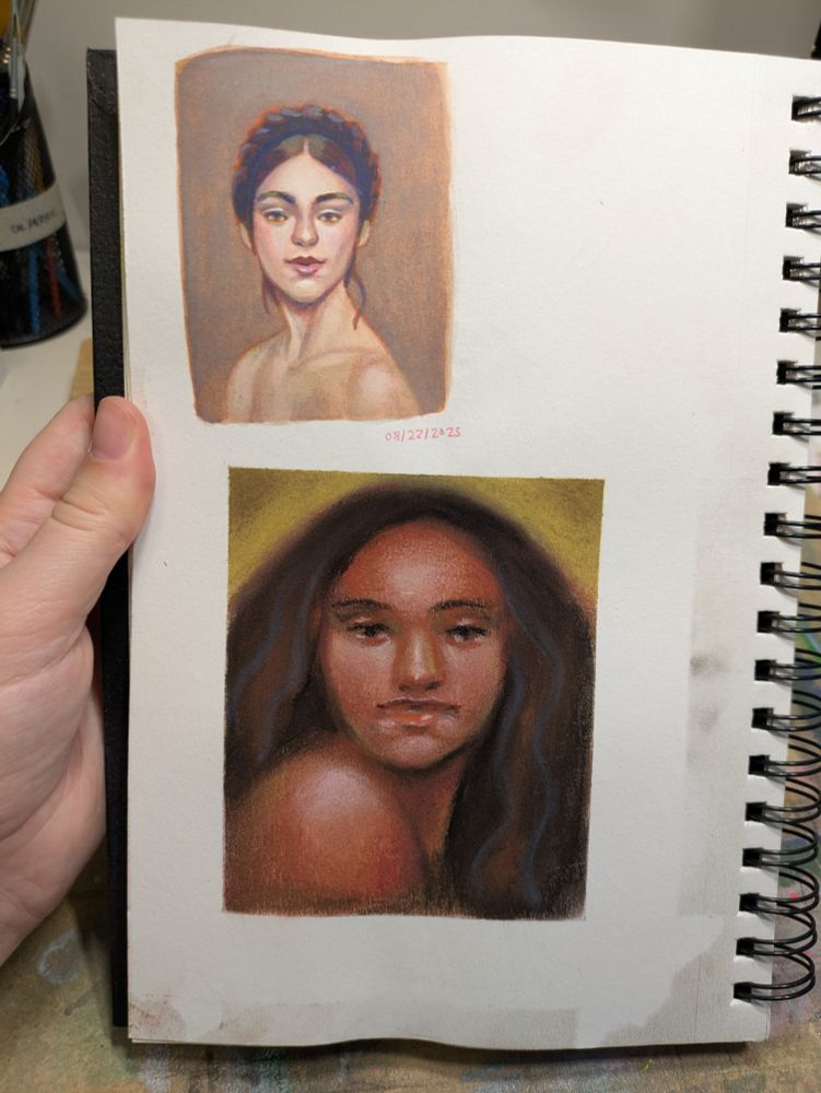 Hand holding a sketchbook with two portraits of women