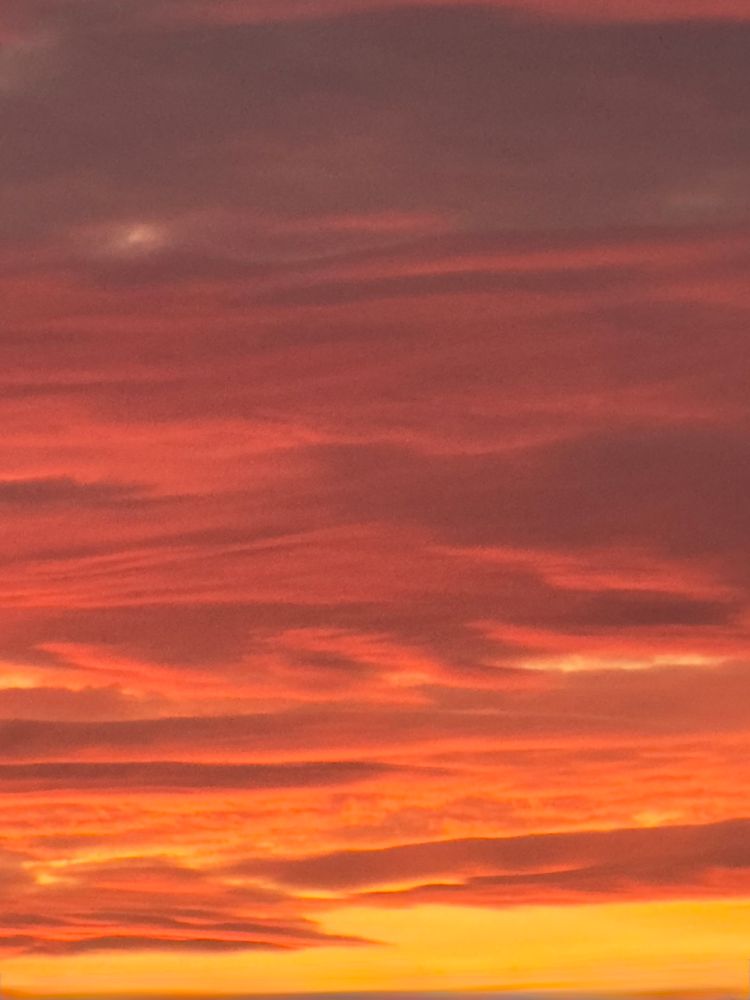 Sky at sunrise. Yellow sky with orange-purple-red clouds, turning deep purple at top. 