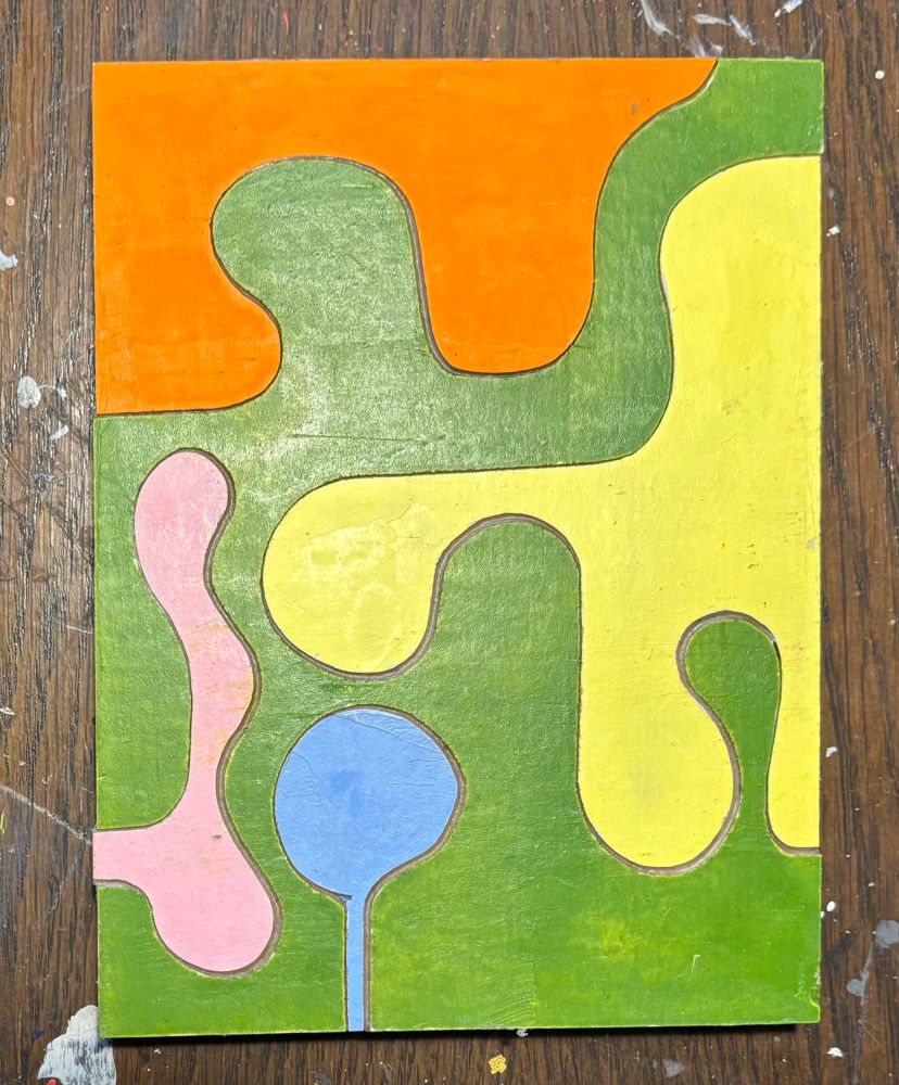 a small painted wood “puzzle” cut into organic shapes. the larger area is a sort of sap green, with smaller shapes in pink, yellow, orange and cerulean blue.
