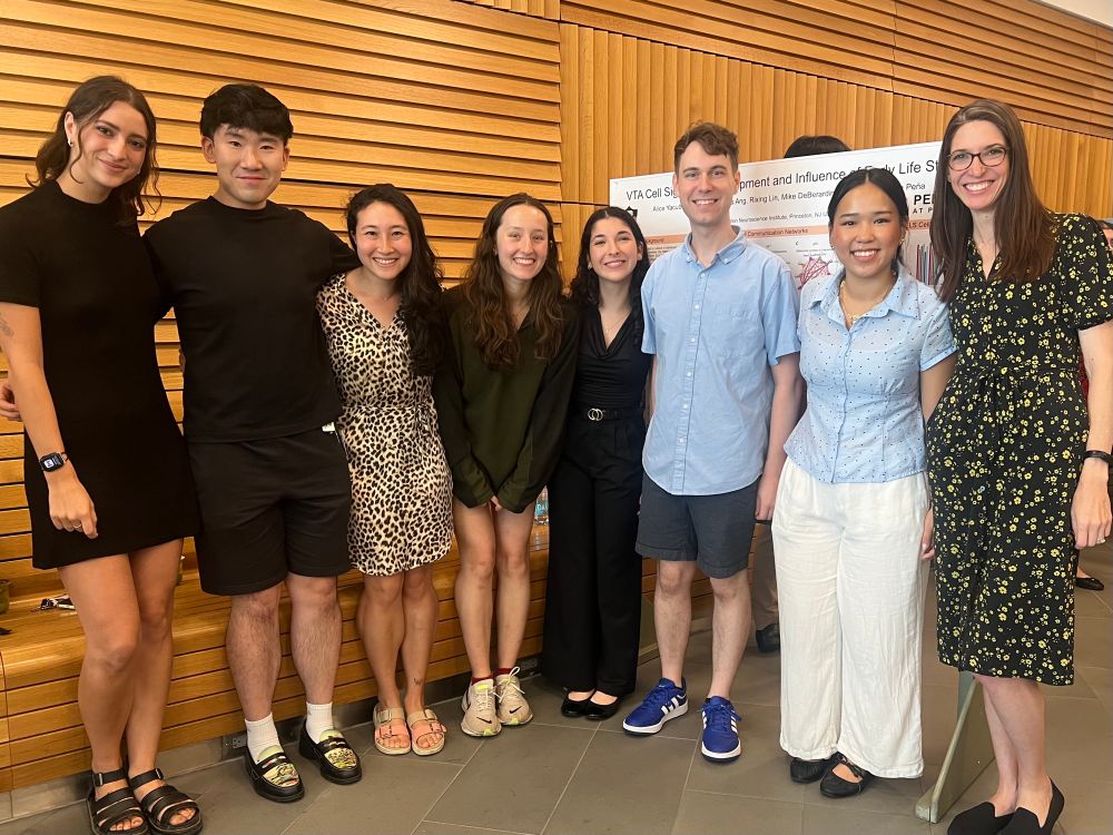 8 members of the Peña lab looking dapper in front of a poster