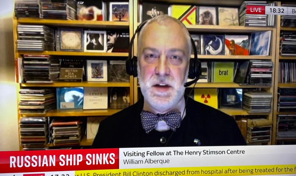 William Alberque, a visiting fellow at the Henry Stimson Centre, on Sky News, in front of a wall of albums. Brat is located near his head.