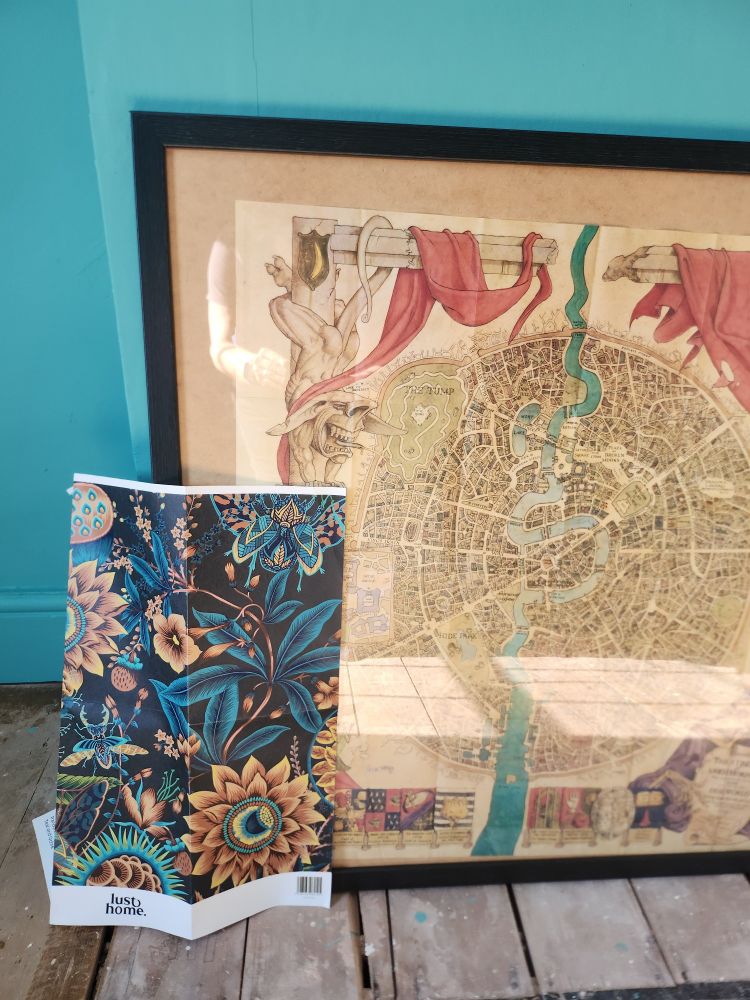 A picture the map of a city on discworld called ankh-morpork, next to teal and gold flower wallpaper which has matching colours to the river