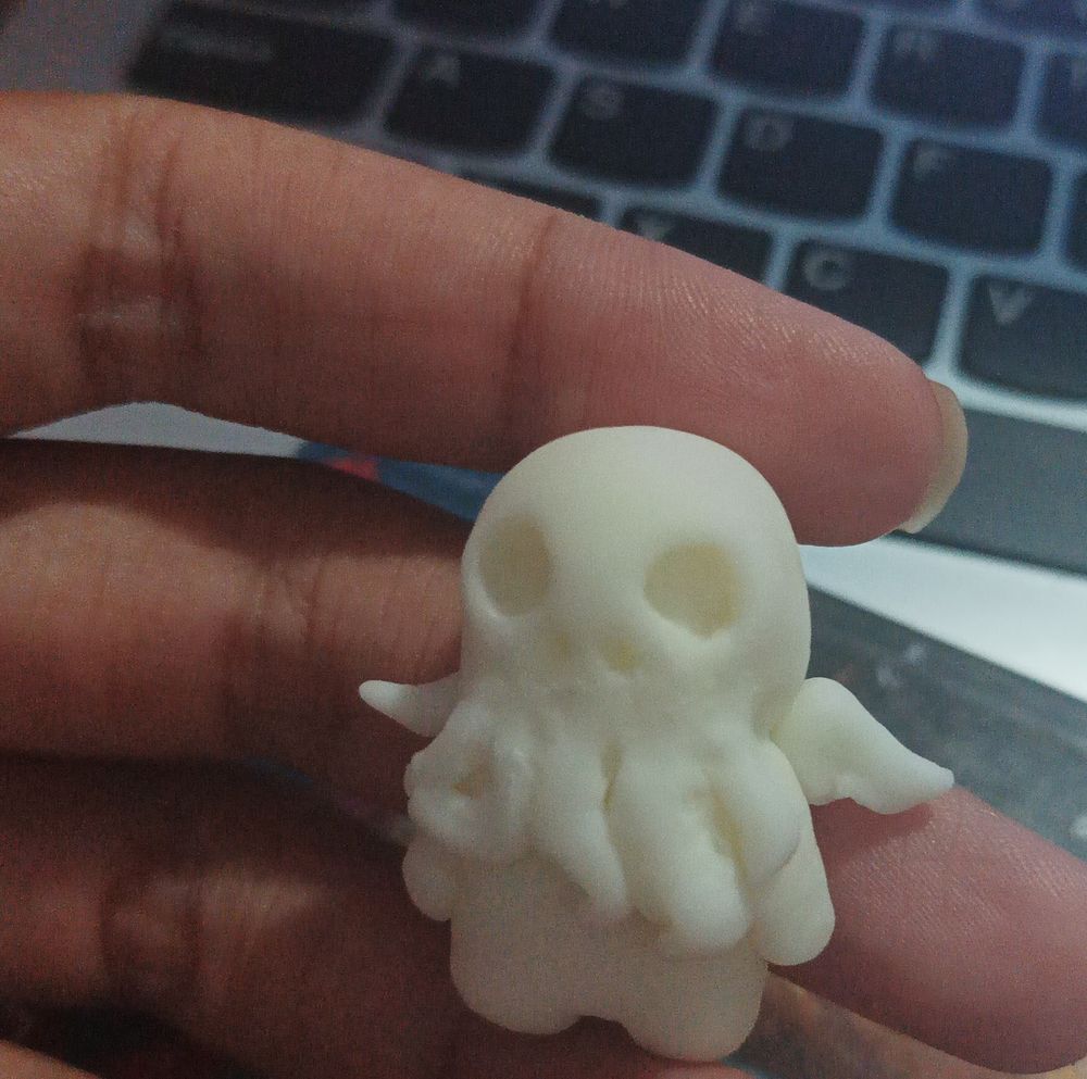 Boneco miniatura do cthulhu feito em biscuit branco, de frente mostrando a cara