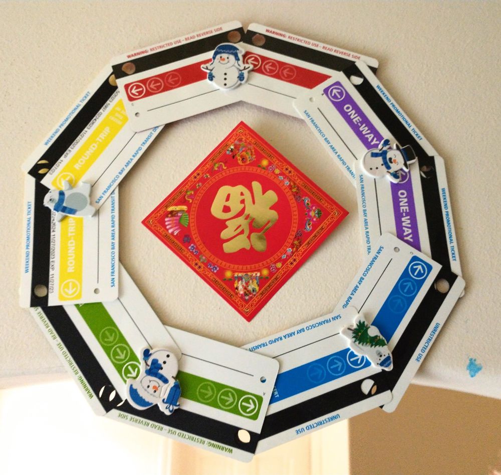 Lunar New Year rotated red paper square that says 福 with a wreath made of multi colored BART tickets and snowmen stickers