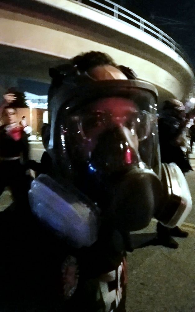 Protester in Los Angeles wearing a full face mask respirator with a plastic face shield, while wearing eyeglasses underneath.