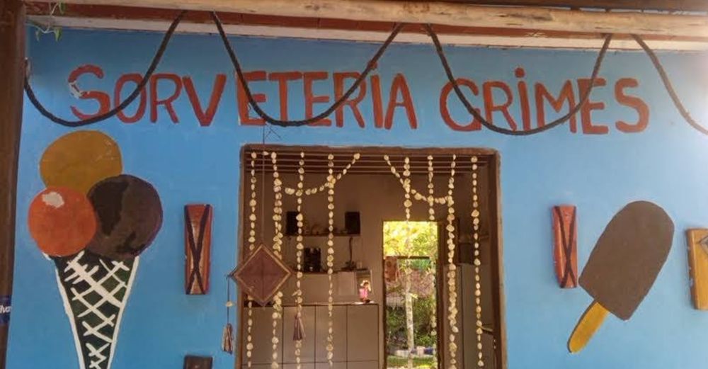 Foto da fachada de um estabelecimento chamado Sorveteria Grimes. Há dois sorvetes desenhados no muro e uma cortina de conchas penduradas paira sobre a entrada.