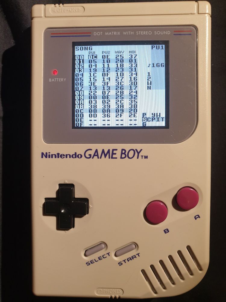 A DMG game boy with a backlit screen running LSDJ, where a banger song is loaded