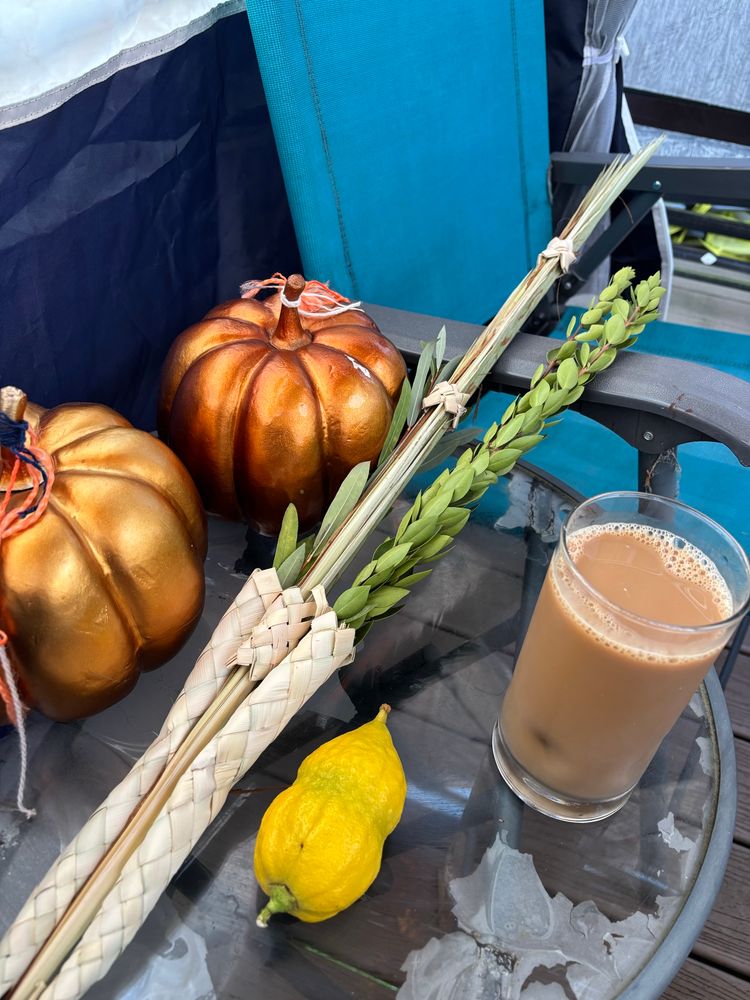 Two sparkly pumpkins, a lulav and etrog, and a coffee. In a sukkah.