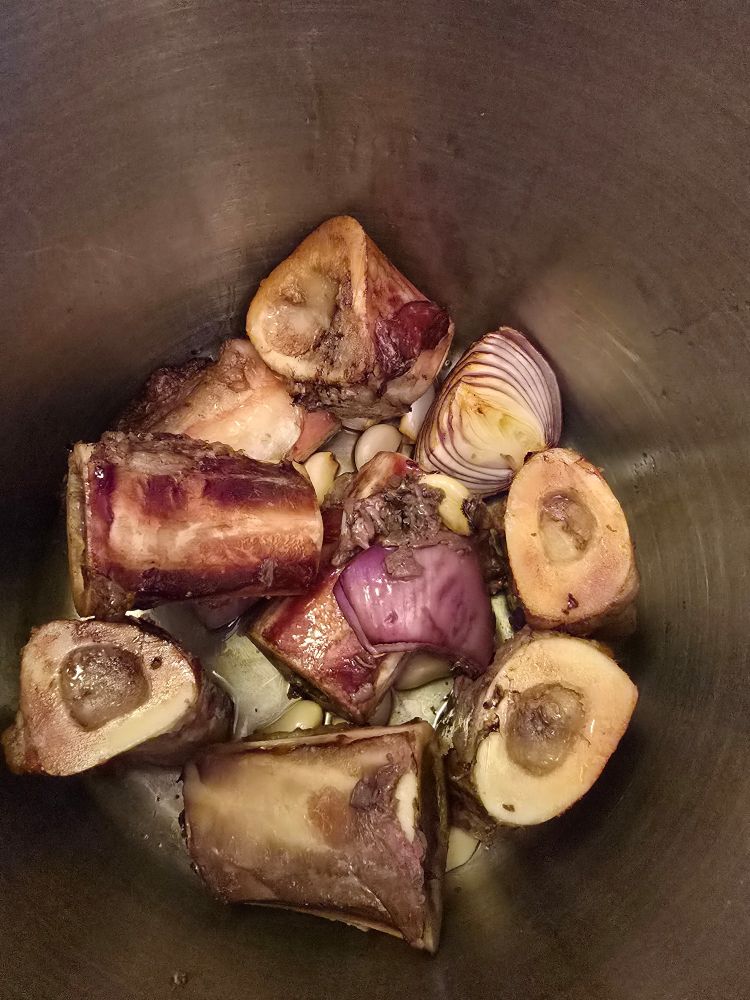 Inside a large pot with beef bones, garlic and onions that have been smoked.