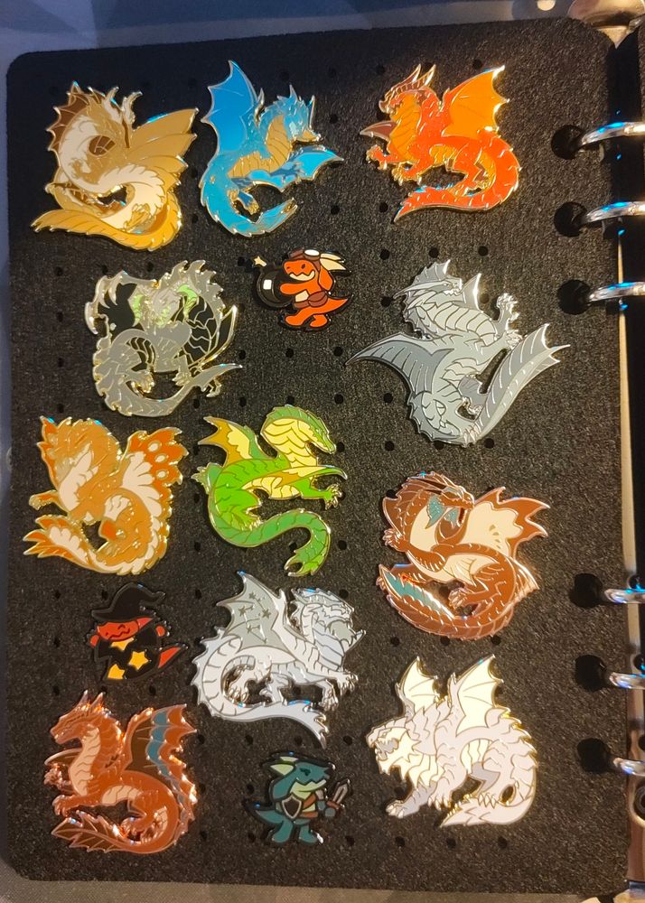 A set of enamel pins, themed around different dragons from dungeons and dragons