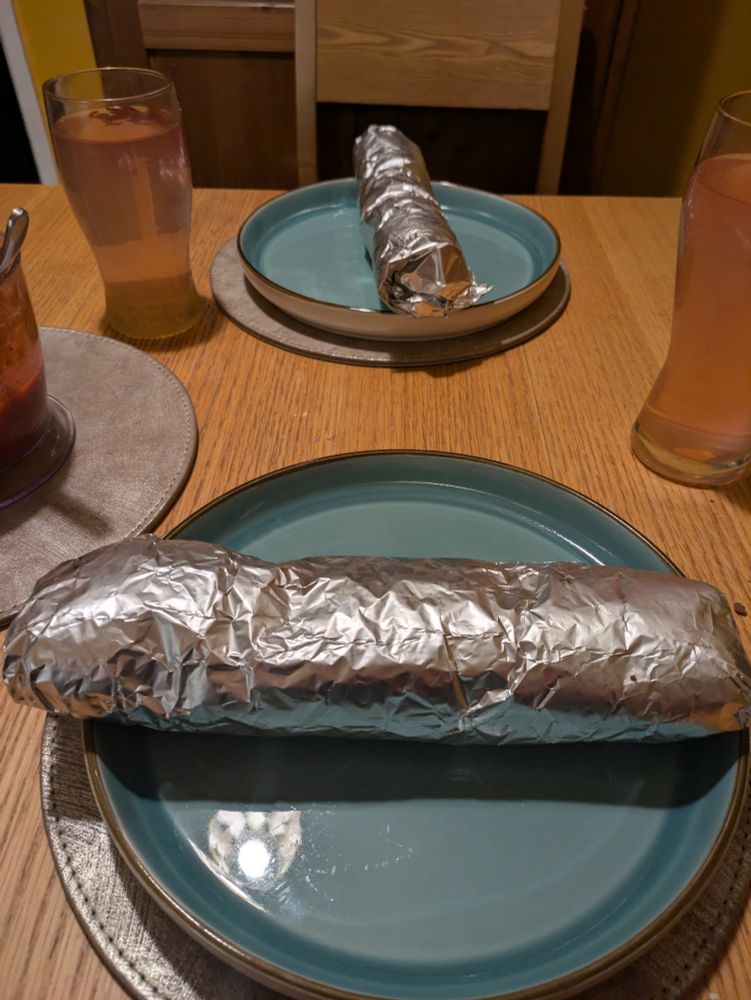 Burrito wrapped in foil on a plate 