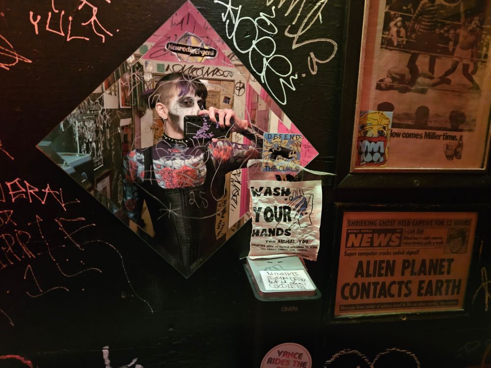 Femme in skeleton body suit and corset in dive bar mirror 