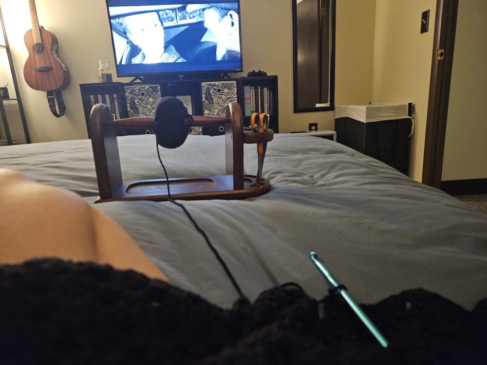 Black yarn becoming a blanket and a black and white movie on tv