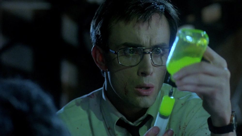 A scene from the horror movie Re-Animator, featuring a glowing drug that brings corpses back from the dead.