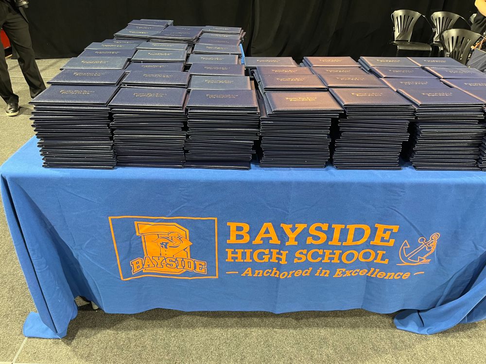 Diploma cases for Bayside HS graduates stacked on a table with a BHS tablecloth