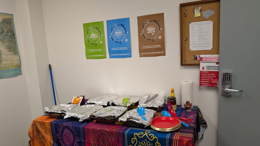 Six trays of food under foil covers for a staff Diwali function.