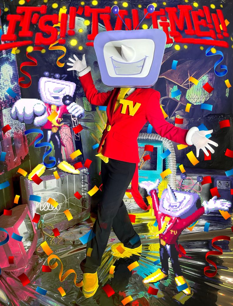 OP dressed as Tenna from deltarune standing up with their arms and hands splayed out and one leg crossed in front of them. they wear a red suit jacket with black pants and yellow shoes, a large yellow tie, white gloves, and a large yellow pin on the suit jacket that says TV. behind the head there is large text that's reads "It's TV Time!" and confetti appearing to fall all around
OP.