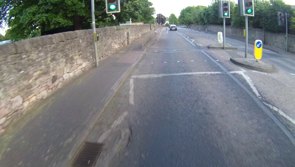 Zig zag markings on the approach to a pedestrian crossing, with a traffic island. The cyclist taking the video is approximately 1.5 metres from the kerb.