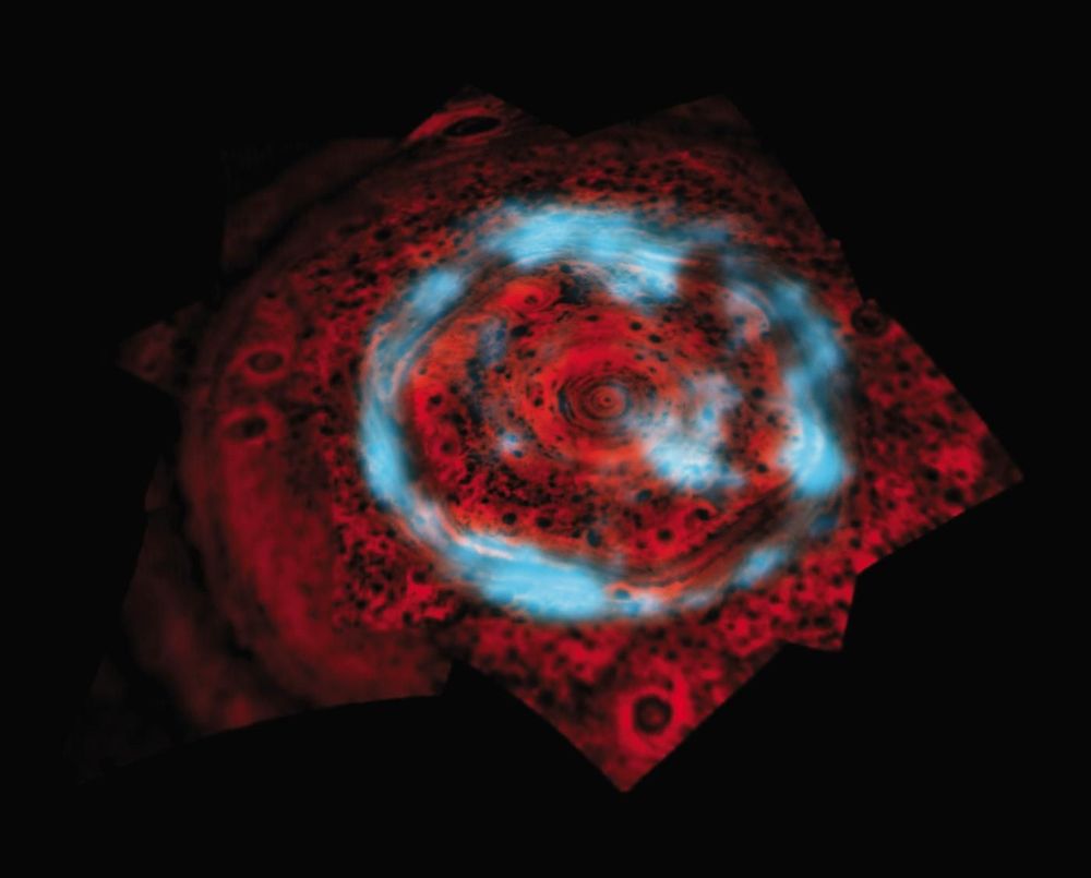The north pole of Saturn with the polar vortex and surrounding cyclones shown in red is surrounded by the faint blue of the gas giant's aurora.