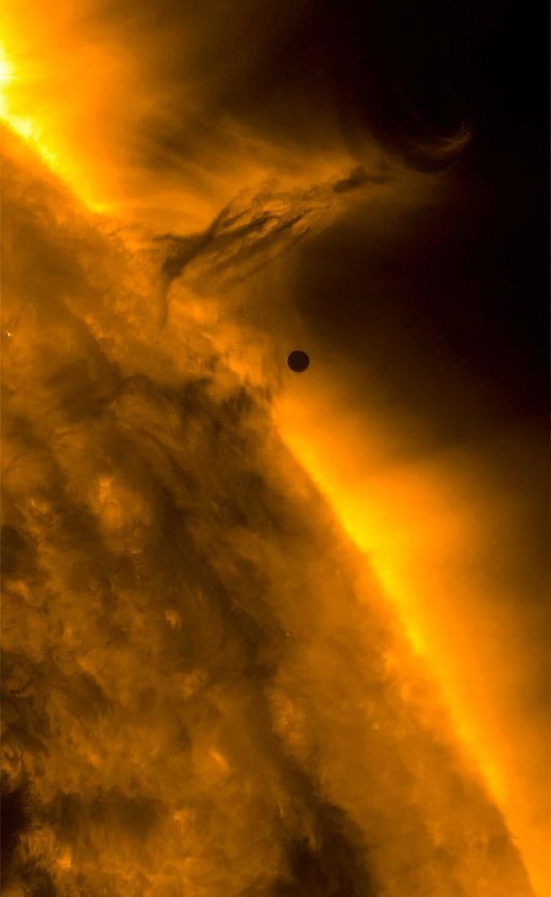 This screen grab from video footage shows a portion of the Sun, complete with a solar flare and bright corona. About two-thirds of the way up the image, a small black dot is in the middle. That's Mercury.