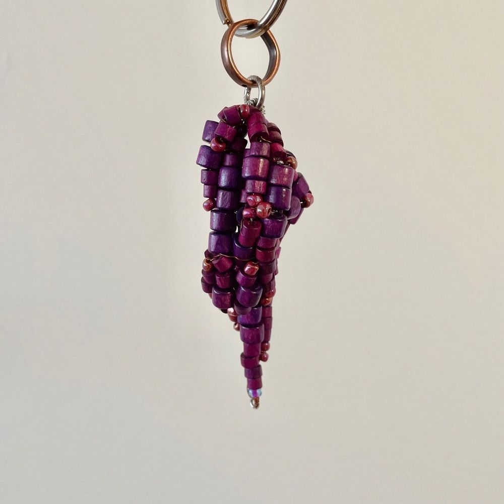 A small sculpture keychain of a purple crystal inspired by The Dark Crystal; made out of small purple beads.