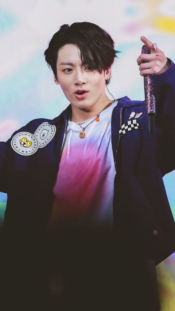 Jungkook holding up his microphone and singing from a PTD concert.