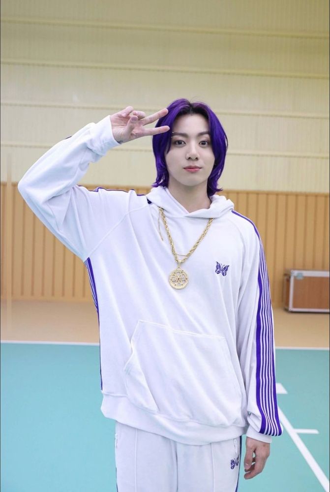 Jungkook in a white track suit with long purple hair on the set of the Butter music video.