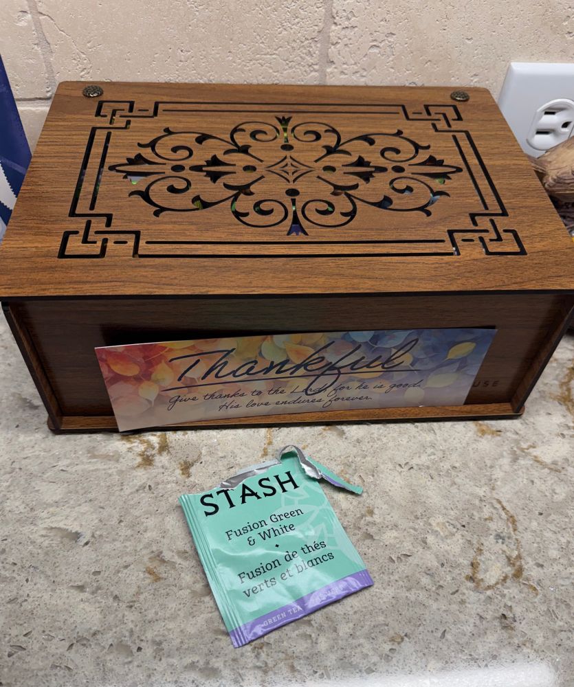 A carved wooden box with a bag of Stash tea open in front of it 