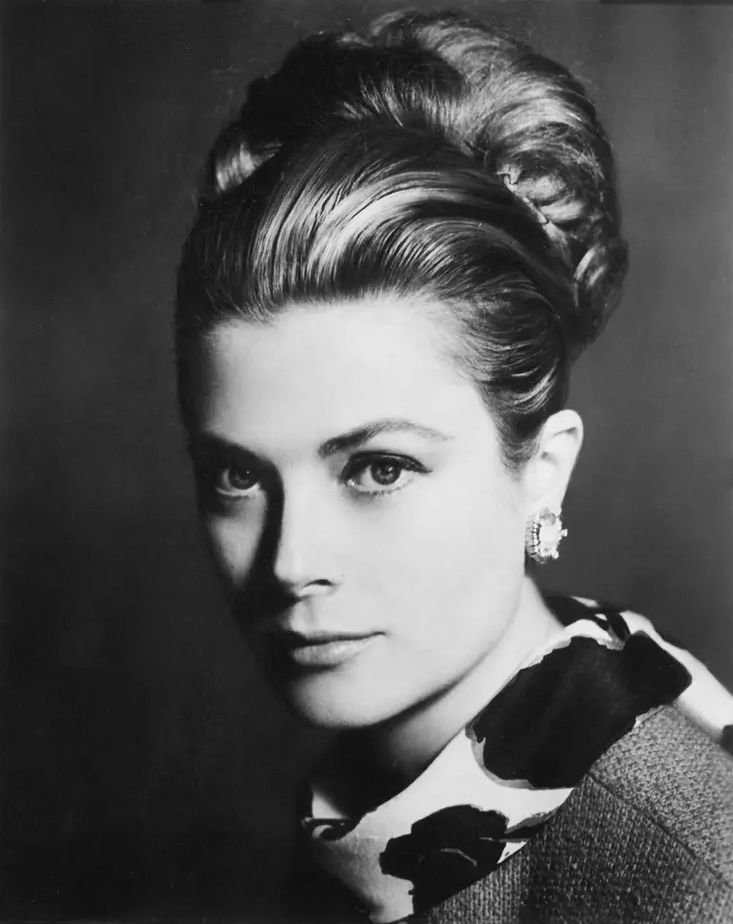 Grace Kelly, Princess of Monaco, gazes softly at the camera with her hair styled in an elegant updo, wearing a floral-patterned scarf and jeweled earrings