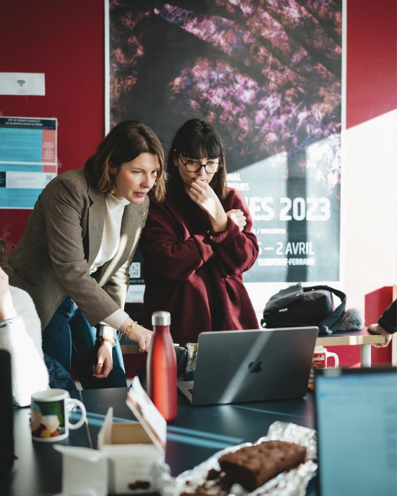Laëtitia avec une personne en formation lors d'un workshop, elles discutent et semblent très concentrées en regardant l'écran d'un ordinateur portable