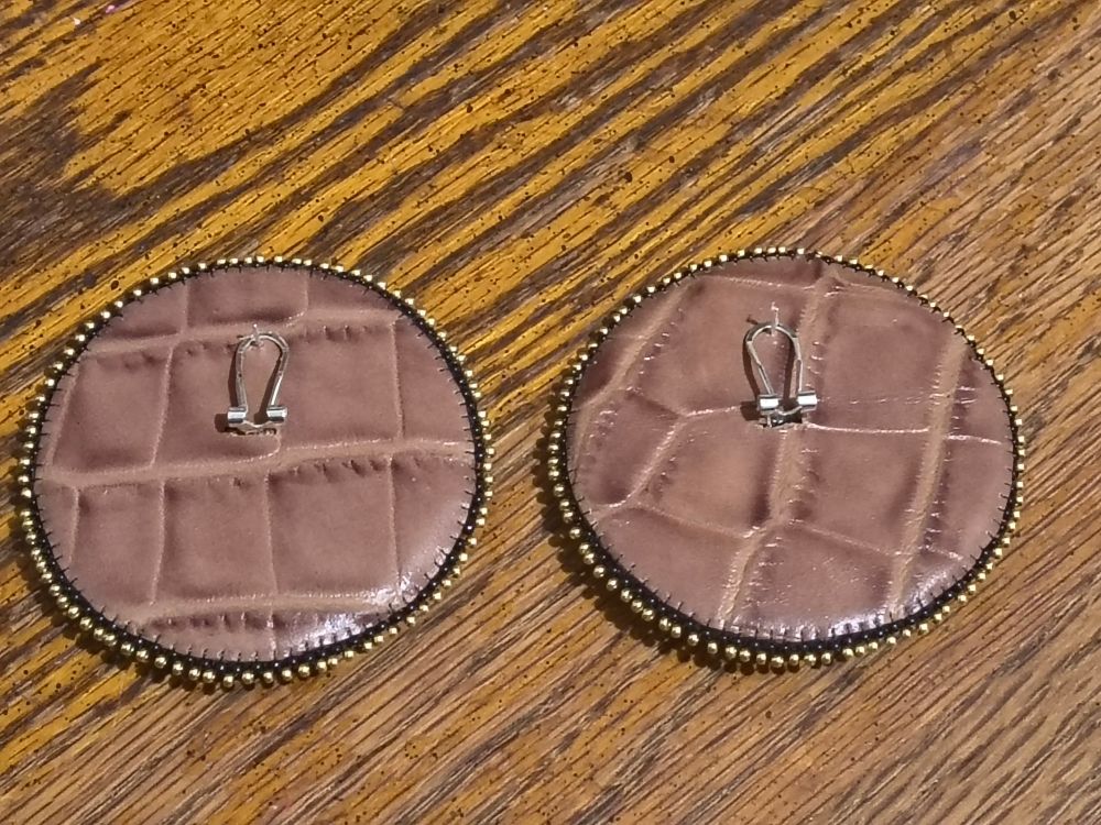 leather back of beaded powwow earrings with gold edging against wooden backgroung