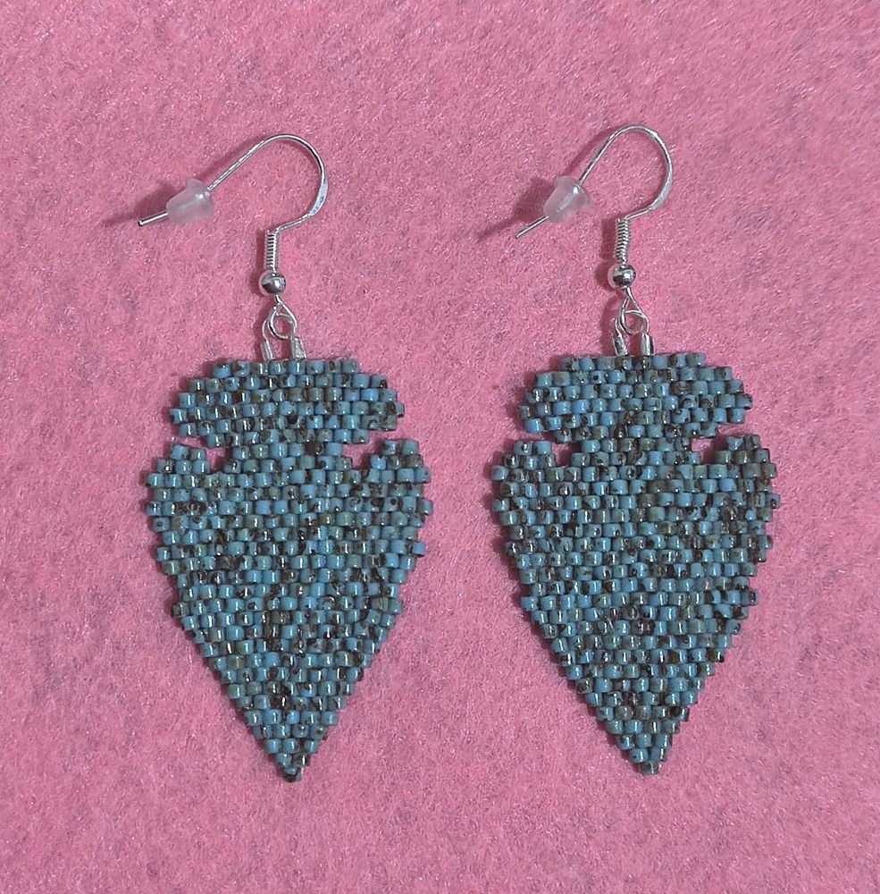 Turquoise colored brick stitch arrowhead themed earrings, silver hooks, pink felt background