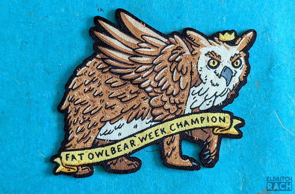 A woven owlbear patch. There is a banner across the owlbear reading 'FAT OWLBEAR WEEK CHAMPION'