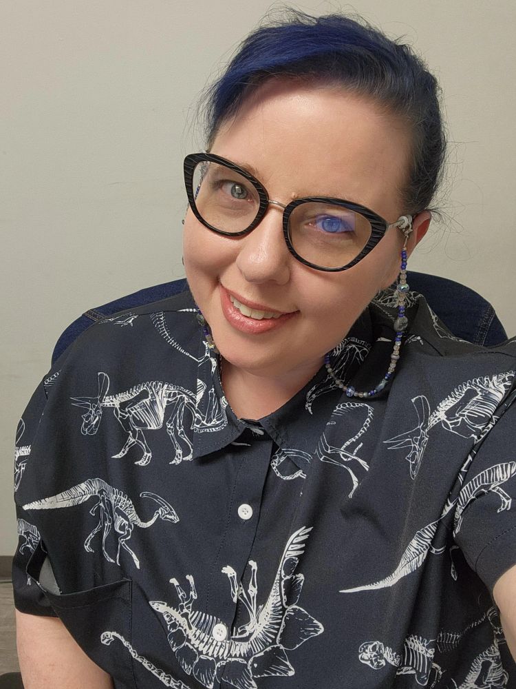 An old, blue haired woman wearing a shirt with DINOSAUR SKELETONS on it 🦕  🦴 