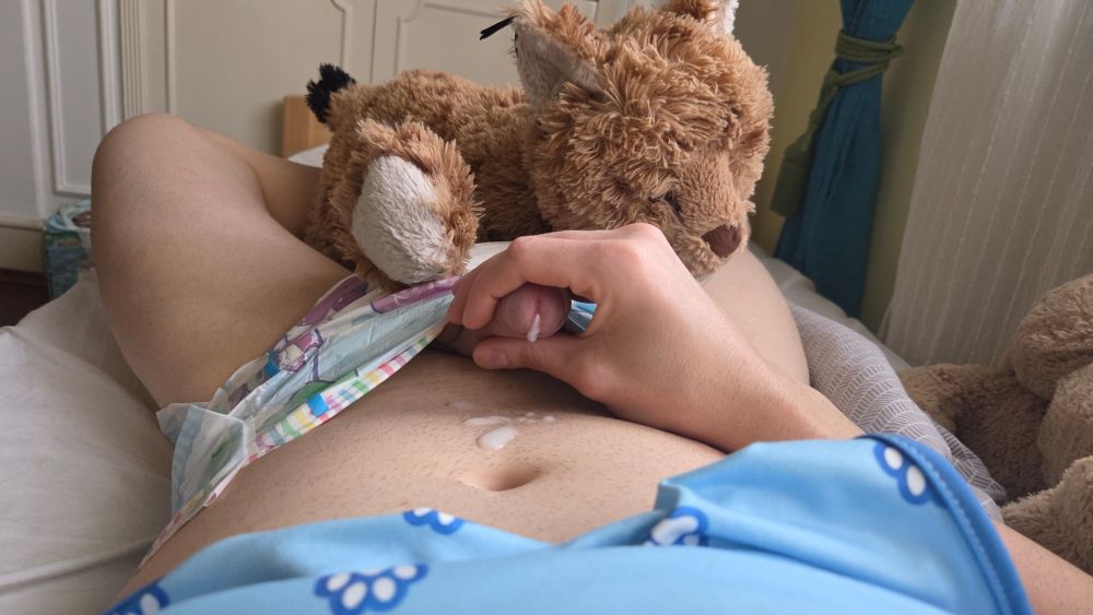 A picture of a penis pointing out of the rainbow colored diaper with semen leaking out on the belly. There's also a plush lynx toy lying on the diaper crotch.