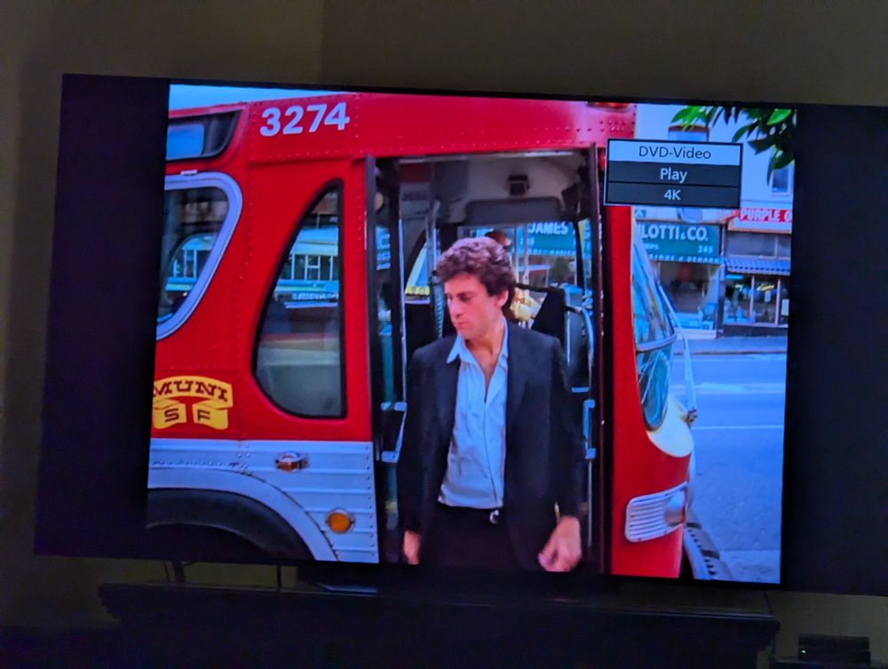 A man steps down from a 1970s red and silver Muni bus in San Francisco.