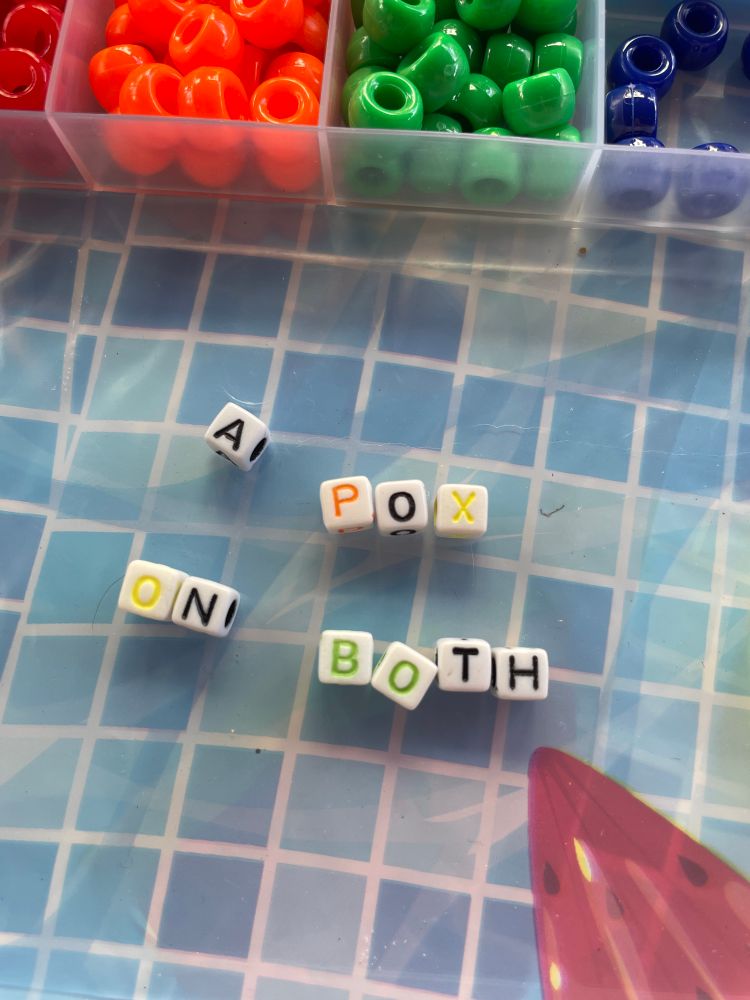 Beads spelling “a pox on both”