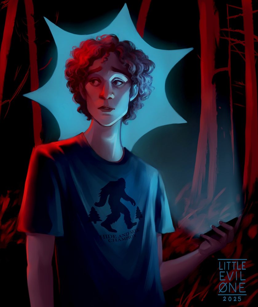 A skinny Curly haired man stands in a red lit forest phone in hand, looking around cautiously. His tshirt features Bigfoot and reads Hide and Seek Champion