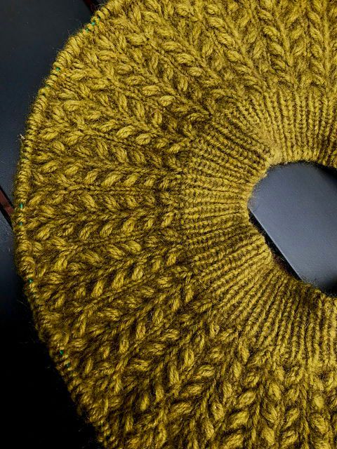 Yellow green patterned sweater yoke on a dark grey table top.