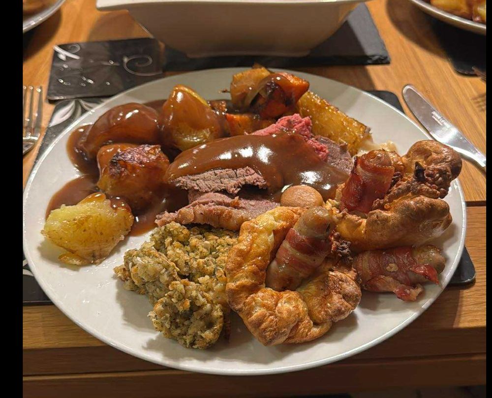 Roast dinner - medium rare beef with gravy, roast potatoes, sausages wrapped in bacon, yorkshire pudding, and something I'm uncertain of