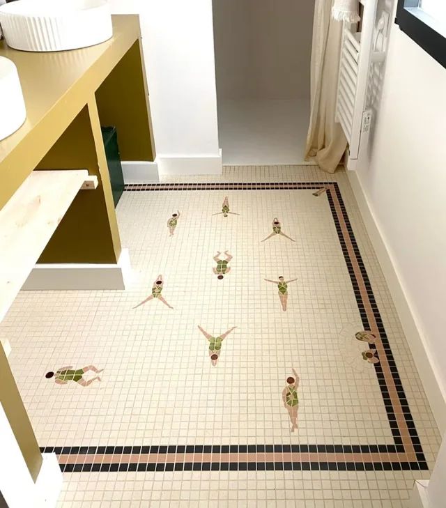 Bathroom tiles with small, swimming people in a green bathing suit scattered across the floor