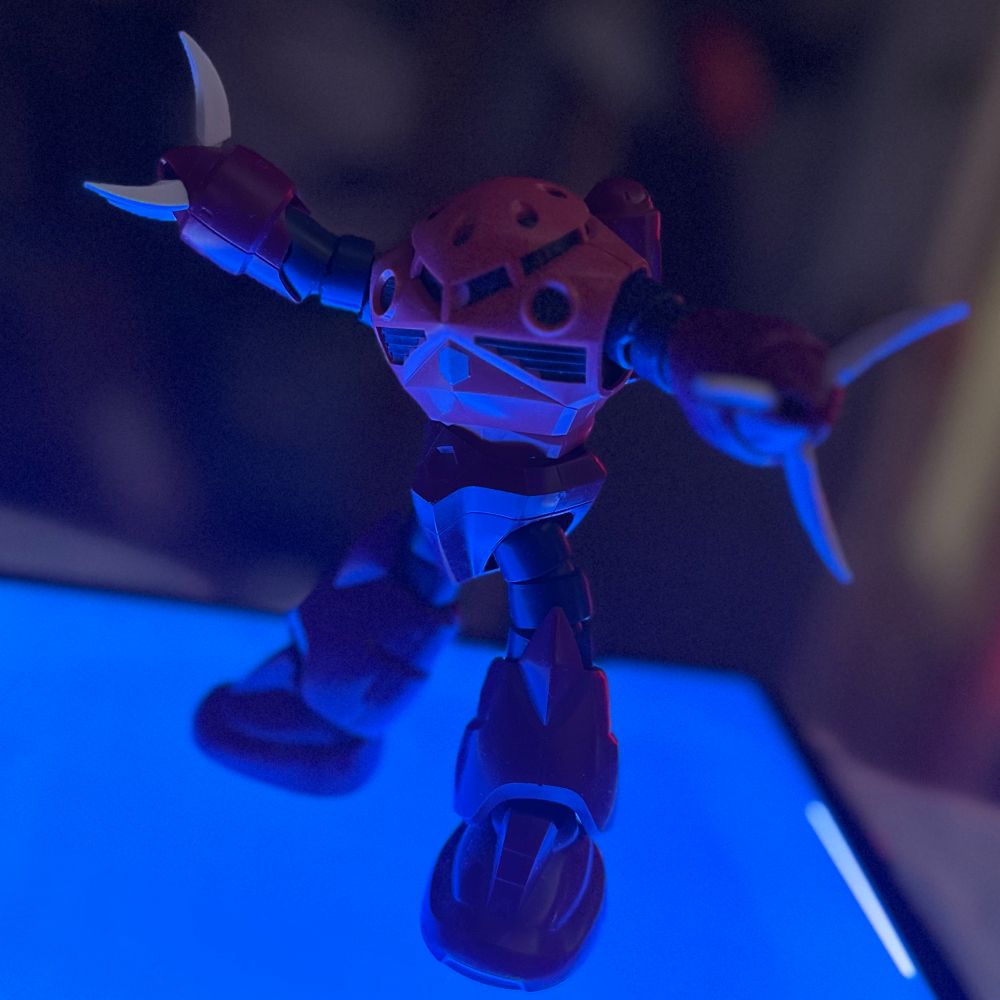 Photo of z’gok gunpla posing. It’s lit underneath by blue lighting.