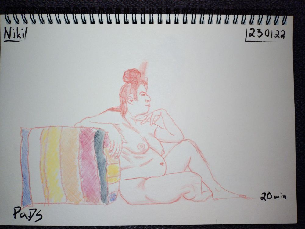 A life drawing picture of a naked woman. She is sitting on the floor with her back leaning to a colourful sofa. Her legs are crossed with one knee up. Her one elbow is resting on the sofa and the other elbow is leaning on her lifted knee.